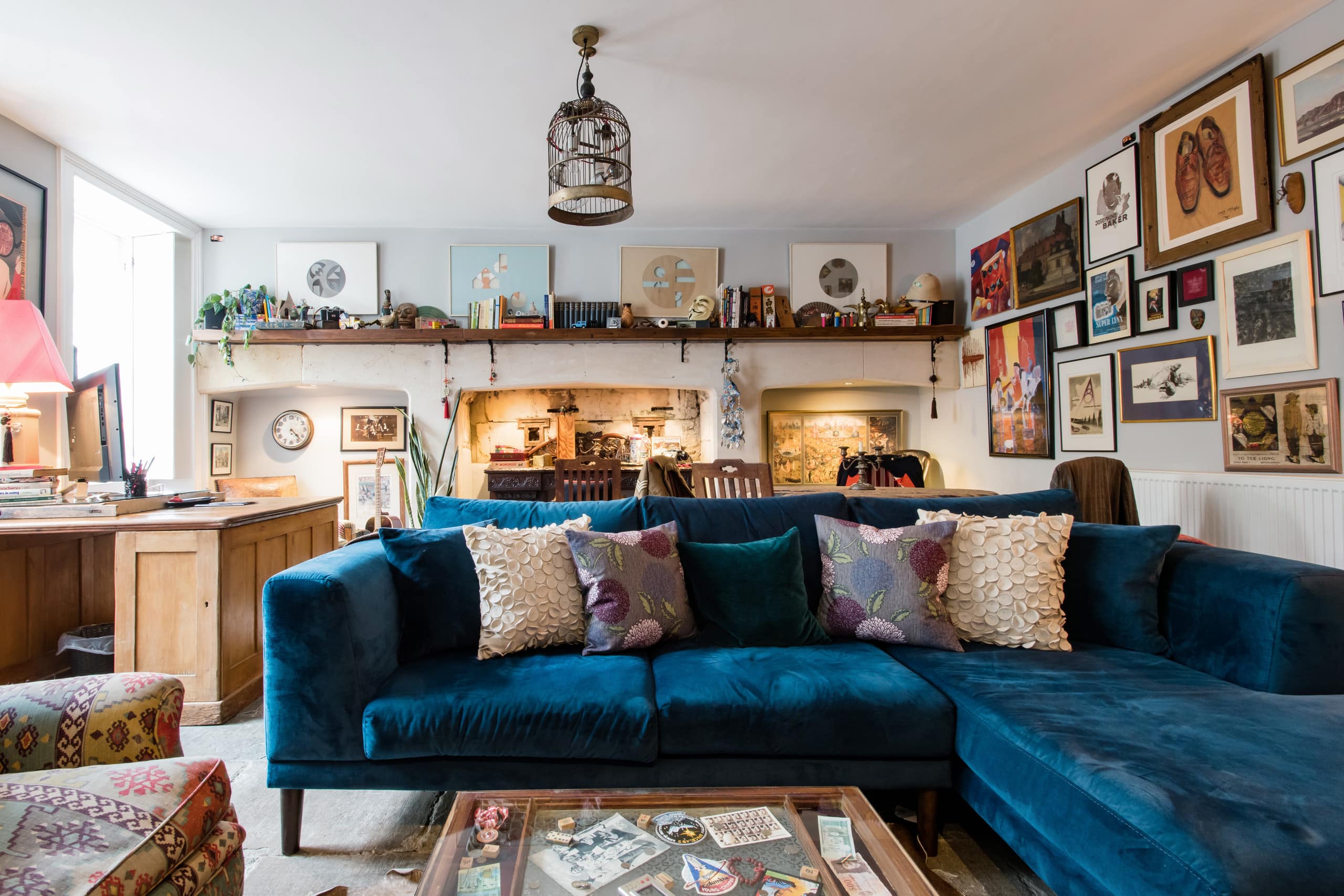 Blue velvet sofa, Georgian kitchen fireplace and collected artwork in the courtyard apartment